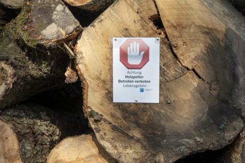 Tree trunks with the sign: Attention wood piles, do not enter, danger to life