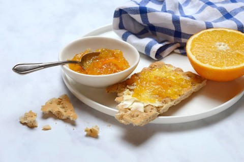 Orange marmalade in small bowls and on crispbread