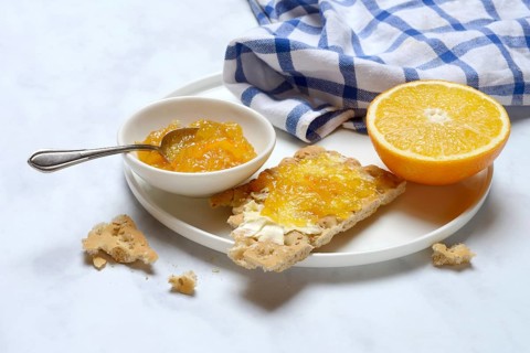Orange marmalade in small bowls and on crispbread