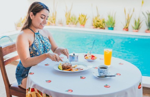 Woman on vacation having breakfast near swimming pool. Breakfast concept near swimming pool, Smiling girl having breakfast near the swim pool