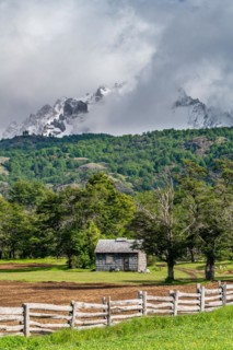 Shingle-roofed wooden house in front of snow-capped mountains, Villa Cerro Castillo, Cerro Castillo National Park, Aysen, Patagonia, Chile, South America