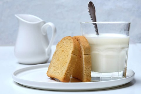 Rusk and glass of milk with spoon