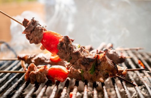 Grilled meat skewers. Close up of homemade roast beef on the grill, Roast beef skewer with tomato. Details of a delicious homemade roast beef