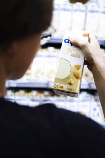 Younger woman buys vanilla almond milk in the supermarket. Radevormwald, Germany, Europe