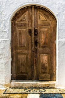 Old wooden doors with pebble mosaics on the floor, winding streets with white houses, Lindos, Rhodes, Greece, Europe