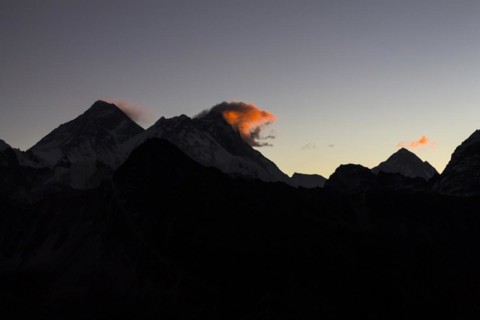 Daybreak at Gokyo Ri. Three clouds mark three eight-thousanders, Mount Everest on the left, Lhotse in the middle and Makalu on the right-hand-side in the greater distance. Silhouette of the mountain r...