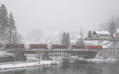 OeBB goods train loaded with ore and the electric locomotive Taurus on the drawbridge over the river Enns in the snowy landscape of Reichraming, Upper Austria, Austria, Europe