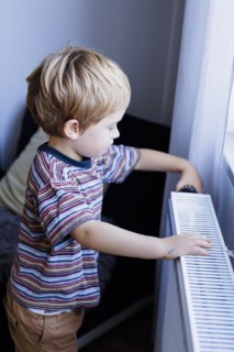 Bonn. Toddler turns the heating thermostat in the childrens room. Bonn, Germany, Europe