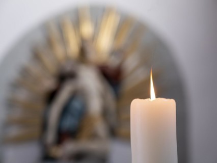 Burning candle in front of a Pieta in the Catholic parish church of St. Peter and Paul, former collegiate church, Romanesque columned basilica, Unesco World Heritage Site, Niederzell on the island of ...