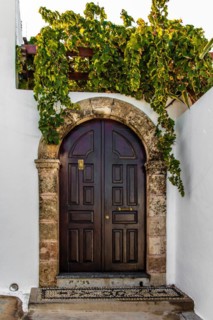Old wooden doors with pebble mosaics on the floor, winding streets with white houses, Lindos, Rhodes, Greece, Europe