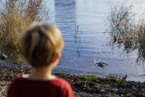 Child playing by a body of water. Bonn, Germany, Europe