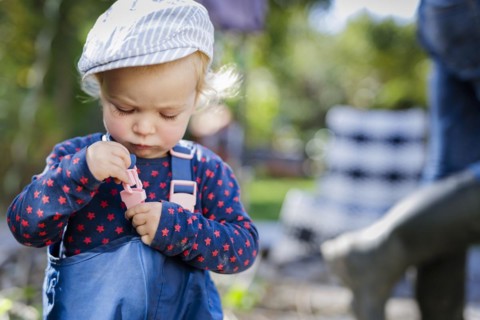 Toddler tries to close the fastener of a pair of play trousers, Bonn, Germany, Europe