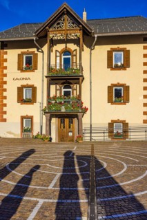 Circular pavement, behind it an older house in Ladin style, with balconies decorated with flowers, Sankt Christina, Val Gardena, Dolomites, South Tyrol, Italy, Europe