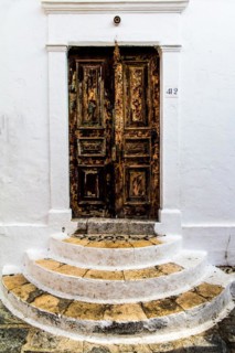 Old wooden doors with pebble mosaics on the floor, winding streets with white houses, Lindos, Rhodes, Greece, Europe