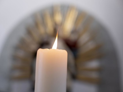 Burning candle in front of a Pieta in the Catholic parish church of St. Peter and Paul, former collegiate church, Romanesque columned basilica, Unesco World Heritage Site, Niederzell on the island of ...