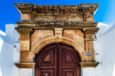 Old wooden doors with pebble mosaics on the floor, winding streets with white houses, Lindos, Rhodes, Greece, Europe
