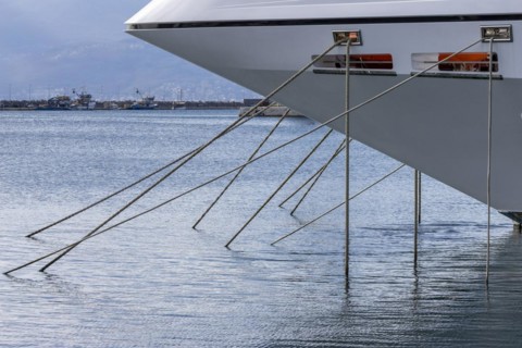 Bow of anchored white yacht with many anchor lines