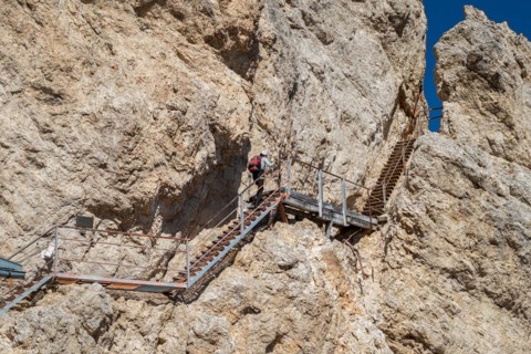 Tourist climbing steel stairs fixed to the rock. Dolomites