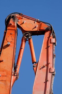 Orange hydraulic excavator arm of an excavator on a construction site