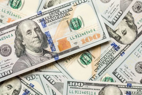 One hundred dollar bills laying on flat surface