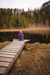 Hiker with backpack sitting on footbridge at lake