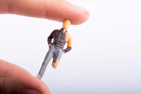 Little man figure with a crippled leg in hand on a white background
