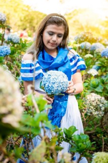 Beautiful Nicaraguan woman in national folk costume holding flowers in a nursery. Portrait of girl in traditional Central American folk costume holding flowers in a nursery. Nicaraguan folk costume