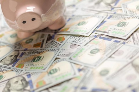 Piggy bank on a bed of one hundred dollar bills with room for your text