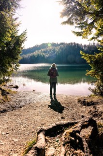 Hiking woman standing at the stand of Alatsee at sunrise