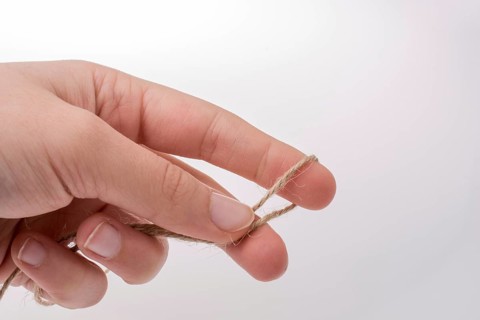 Hand holding linen thread on a white background