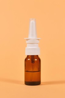 Brown glass nasal spray bottle on yellow background