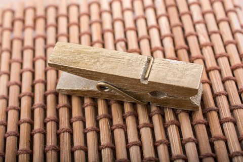 Small wooden clothespin placed on straw background