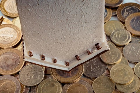 Turkish Lira coins by the side of a model house on white background