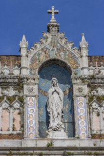 Detail of the top of the facade of the Capuchin Church of Our Lady of Lourdes with a statue of Our Lady of Lourdes decorated with a mosaic