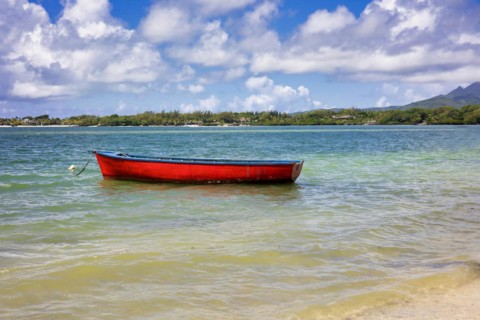 Red fishing boat lies tied up near the beach
