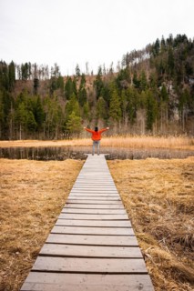 Male hiker on footbridge in front of lake