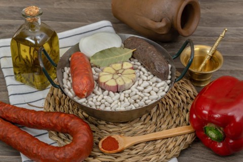 Raw white beans in metal casserole with all the ingredients for cooking them