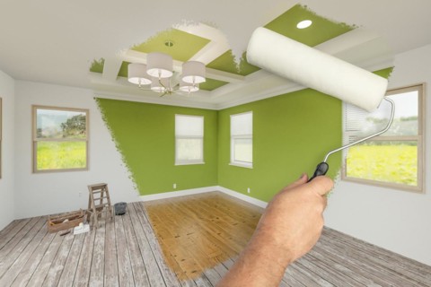 Before and after of man using A paint roller to reveal newly remodeled room with fresh green paint