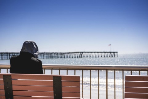 Rear view of a man sitting near Venturas pier and looking at it