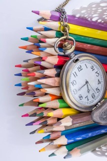Retro style classic pocket watch and color pencils on white background