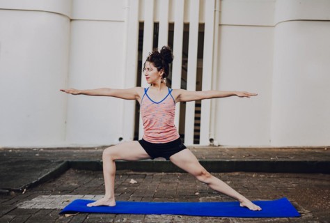 Girl practicing yoga Warrior II pose outdoors. Latin woman doing yoga warrior pose outdoors. Young woman doing yoga virabhadrasana II outdoors