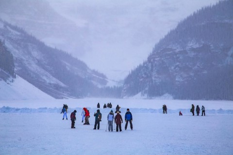 Ice skaters on the frozen mountain lake Lake Louise near Castle Hotel Chateau Lake Louise