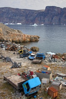 Rubbish and car wrecks at garbage dump and icebergs at the fishing village Uummannaq