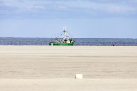 Crab cutter on the North Sea coast and sandy beach at low tide