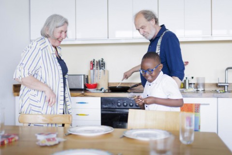 Temporary grandparents. Elderly couple volunteer to look after a boy from Africa for a few hours a week