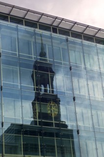 The tower of St. Michaels Church is reflected in the facade of a high-rise office building