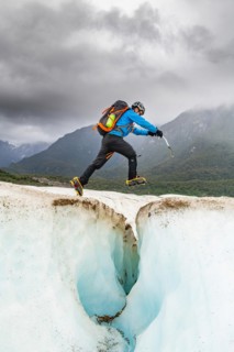 Hiker jumps over an ice crevasse
