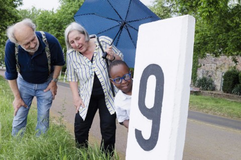Temporary grandparents. Elderly couple volunteer to look after a boy from Africa for a few hours a week.