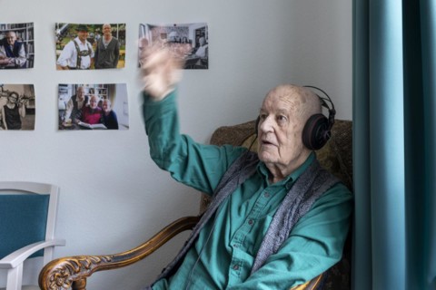 Old man in nursing home conducts to music