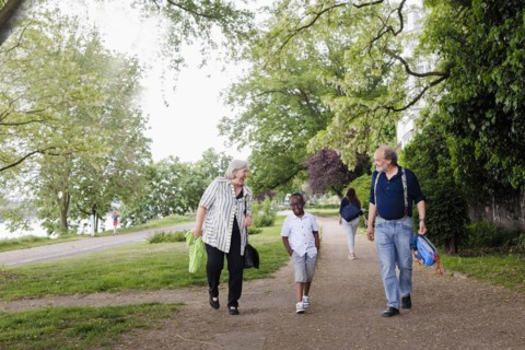 Temporary grandparents. Elderly couple volunteer to look after a boy from Africa for a few hours a week.
